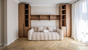 Una stanza con un divano, mensole in legno e una finestra con tende.