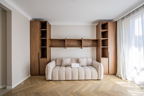 A room with a sofa, wooden shelving, and a window with curtains. - Premium-New mobility lease-Paris16th-2bedroom (Paris)