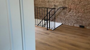 A room with a stone wall, a wooden floor, and a black metal staircase. - Our small chalet in the heart of the Palatinate Forest. Relaxation, hiking, romance. (Lindenberg)