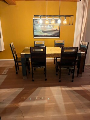 Un comedor con una mesa, sillas, un cuadro en la pared y una lámpara colgante.