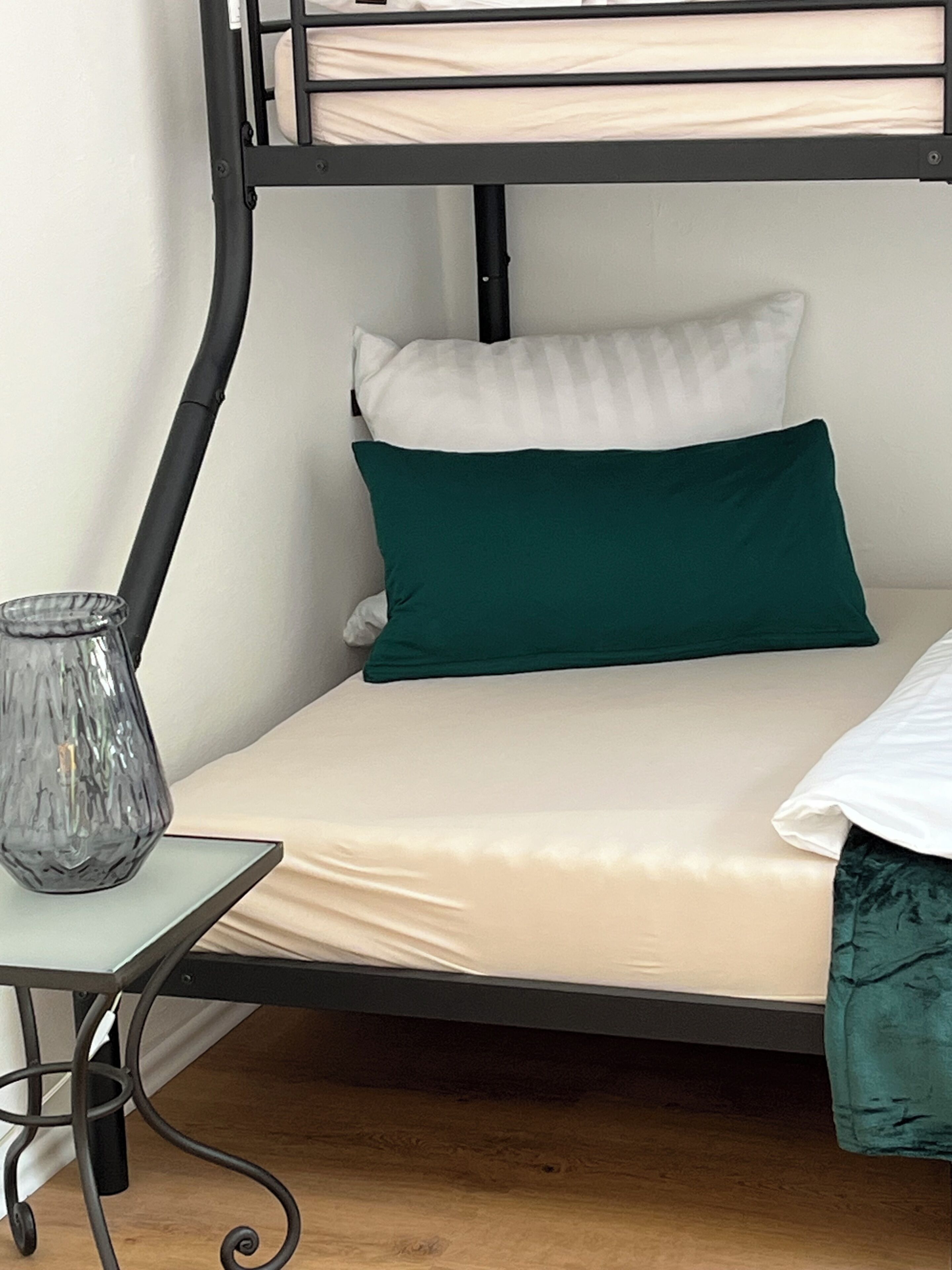 Un lit superposé avec un vase en verre posé sur une petite table à côté.
