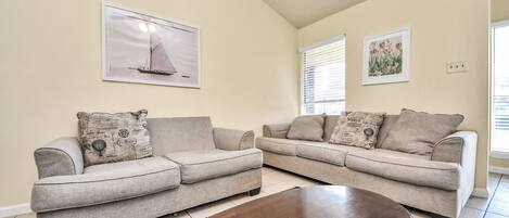 A living room with two sofas, a coffee table, and wall art.