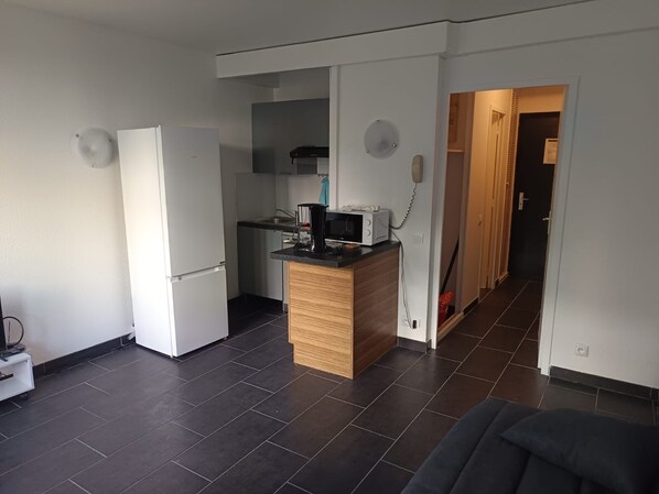 Eine kleine Küche mit Kühlschrank, Mikrowelle und einer Holz Arbeitsplatte.