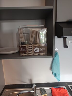 Eine Küche mit einem Regal, das eine Reihe von Küchenutensilien und eine mit 'Géo Secret Gourmet' beschriftete Schachtel enthält.