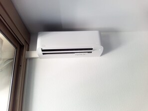 En hvid aircondition-enhed monteret på en væg.