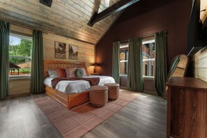A bedroom with a wooden ceiling, a large bed with pillows, a nightstand, and a view of the outside. - Pool, Hot tub, Game Room, Gazebo, Sleeps 36 (Sevierville)