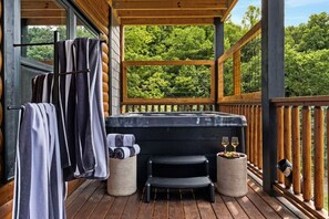 A wooden deck with a hot tub, towels, and a small table with glasses and fruit. - Pool, Hot tub, Game Room, Gazebo, Sleeps 36 (Sevierville)