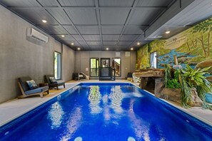 An indoor swimming pool with a mural, lounge chairs, and a staircase leading to a balcony. - Pool, Hot tub, Game Room, Gazebo, Sleeps 36 (Sevierville)