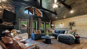 Una sala acogedora con chimenea, sillones de cuero, un sofá oscuro y una pared de piedra.