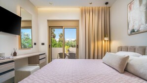 Une chambre d’hôtel avec un grand lit, un bureau avec des tiroirs, un téléviseur à écran plat, une grande fenêtre et un balcon avec vue.