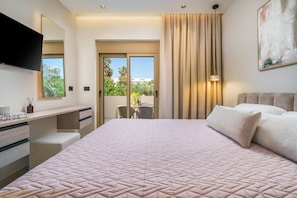 A hotel room with a large bed, a desk with drawers, a flat-screen TV, a large window, and a balcony with a view. - MS Beach Luxury Homes - Manolis (Kos)