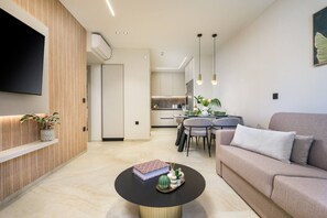 A modern living room with a sofa, a coffee table, and a dining area with chairs and a table. - MS Beach Luxury Homes - Manolis (Kos)