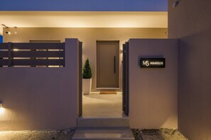 A modern building entrance with a gated driveway, a potted plant, and a sign reading 'MS MANOLIS.' - MS Beach Luxury Homes - Manolis (Kos)
