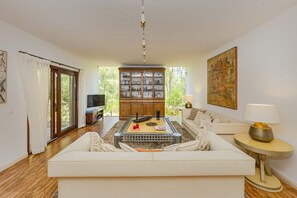 Ein Wohnzimmer mit einer Couch, einem Couchtisch, einem Schrank und einem Fernseher.