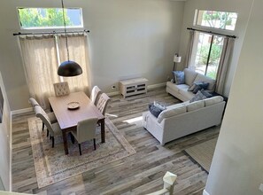 Ein Essbereich mit Holztisch und -stühlen, einer Couch und einem Teppich.