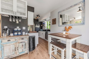 A kitchen with white cabinets, a wooden table, and a mirror.
