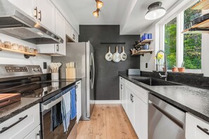 A modern kitchen with a stainless steel refrigerator, a double oven, and a black countertop.
