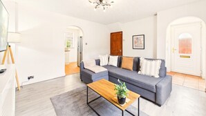 Un salon avec un canapé gris, une table basse en bois et un luminaire suspendu au plafond.