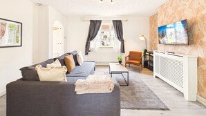 Un salon avec un canapé, une table basse, un téléviseur et un radiateur.
