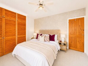 A bedroom with a bed, wooden wardrobe, nightstand, lamp, and a ceiling fan. - Hatfield Retreat | Parking | Spacious | Sleeps 5 (Hertfordshire)