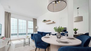Een moderne eethoek met een ronde tafel, blauwe stoelen en uitzicht op de stad.