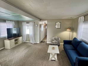 Una sala de estar con televisor, sofá, mesa de centro y un sillón estampado.