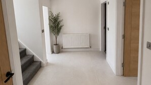 Un couloir avec un radiateur, une plante en pot et un escalier.