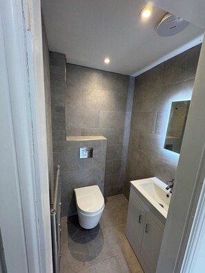 Une salle de bain moderne équipée de toilettes, d’un lavabo et d’un miroir.