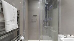 A modern bathroom with a glass shower enclosure, a towel rack, and a toilet paper holder. - Blue Door Stay - 5 Bedroom Apartment in London, UK (London)