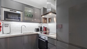 A modern kitchen with stainless steel appliances, a microwave, a coffee maker, and a built-in oven. - Blue Door Stay - 5 Bedroom Apartment in London, UK (London)