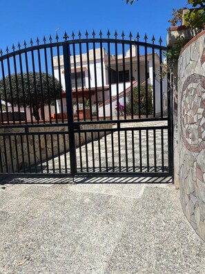 A gated entrance with a stone wall and a building in the background. - Villa Clelia in Salento for 12 guests near the sea (San Pietro in Bevagna)