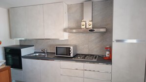 Una cocina moderna con microondas, estufa a gas, fregadero y armarios.