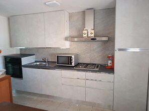 A modern kitchen with a microwave, gas stove, sink, and cabinets. - Villa Clelia in Salento for 12 guests near the sea (San Pietro in Bevagna)