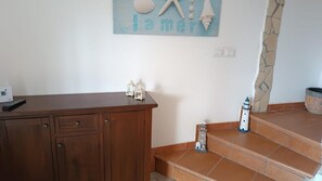 A wooden cabinet with drawers, a small table with a remote control, and a decorative wall piece with shells and the word 'lamer'. - Villa Clelia in Salento for 12 guests near the sea (San Pietro in Bevagna)