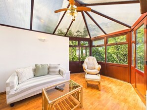 A room with a glass ceiling, a sofa, a chair, and a coffee table.