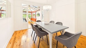 A dining area with a table and chairs, a chandelier, and a view through an open door.