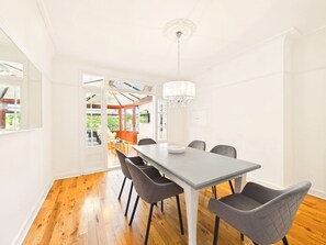 A dining area with a table and chairs, a chandelier, and a view through an open door.