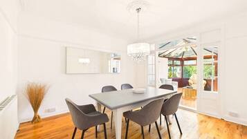 A dining area with a table and chairs, a chandelier, and a view through an open door to an outdoor space.