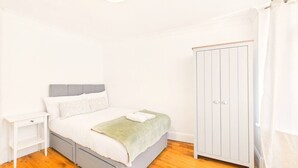 A bedroom with a bed, nightstand, wardrobe, and a hanging light fixture.