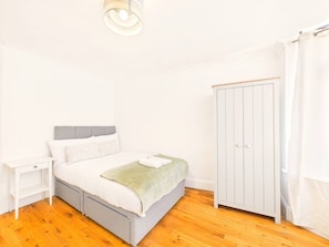 A bedroom with a bed, nightstand, wardrobe, and a hanging light fixture.