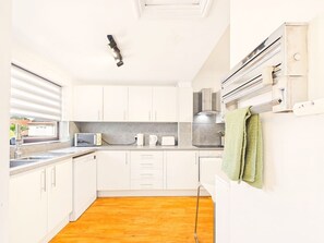 A compact kitchen with white cabinets, a built-in microwave, and a coffee maker. - Spacious Enfield Stay | Double Garage | Sleeps 6 (Greater London)