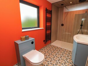 A bathroom with a toilet, a window, a towel rack, and a shower area. - The Cozie Sow (Yeovil)