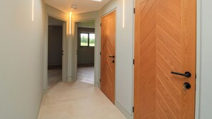 A hallway with two wooden doors, a ceiling light, and a view through a window. - The Cozie Sow (Yeovil)