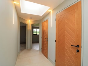 A hallway with two wooden doors, a ceiling light, and a view through a window.