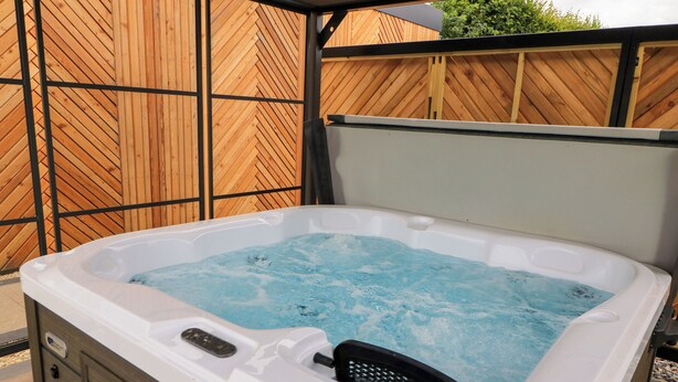 A hot tub with a wooden fence in the background. - The Cozie Sow (Yeovil)