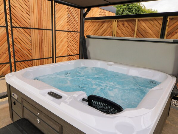 A hot tub with a wooden fence in the background.