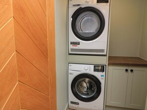 A stacked washer and dryer unit with a wooden panel wall and a countertop.