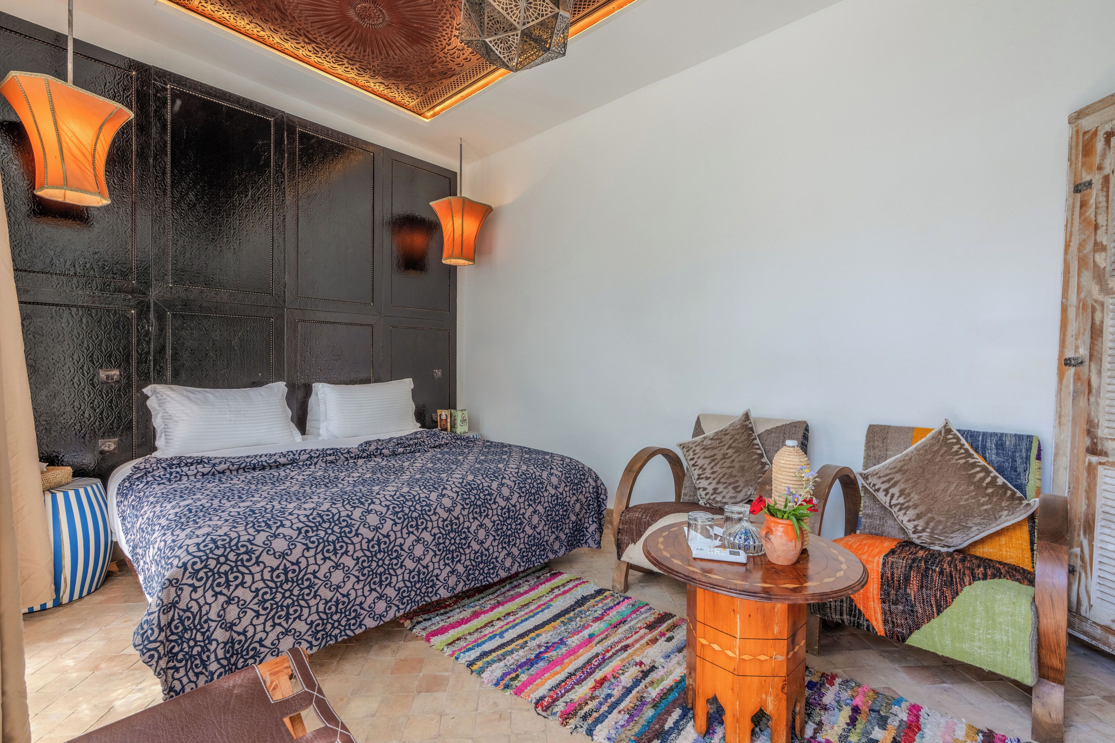 A bedroom with a large bed, a sofa, a small table, and a patterned rug.