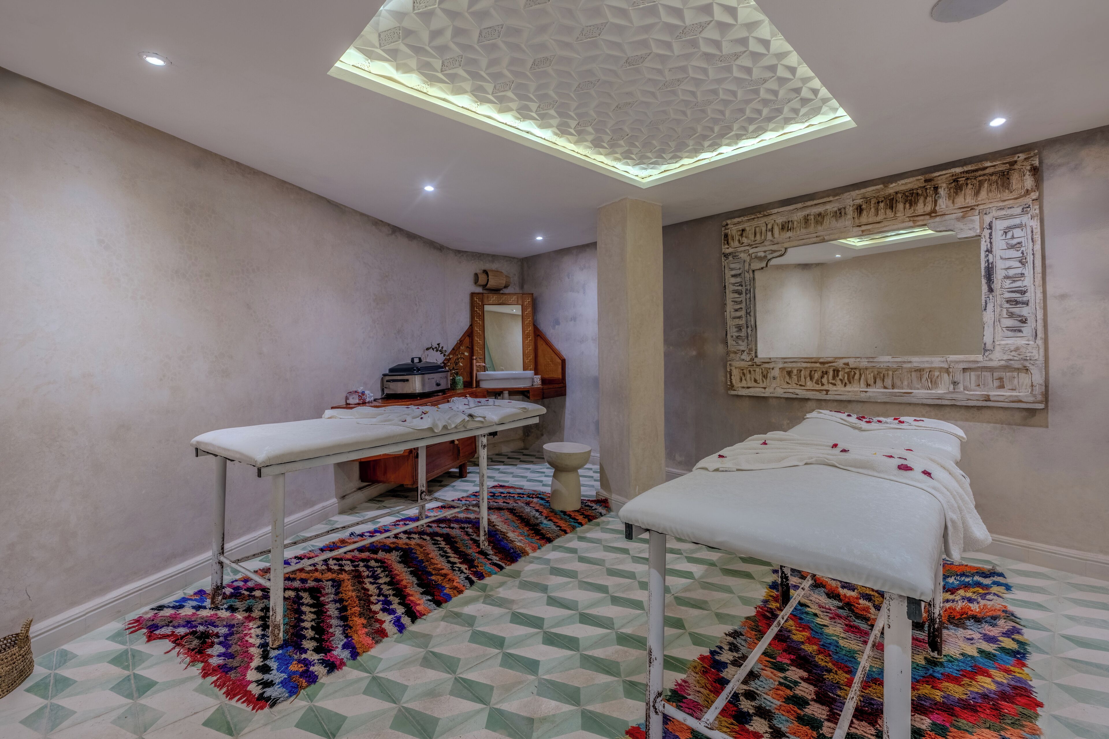 A room with a large mirror, a bench, a table, and a patterned rug.