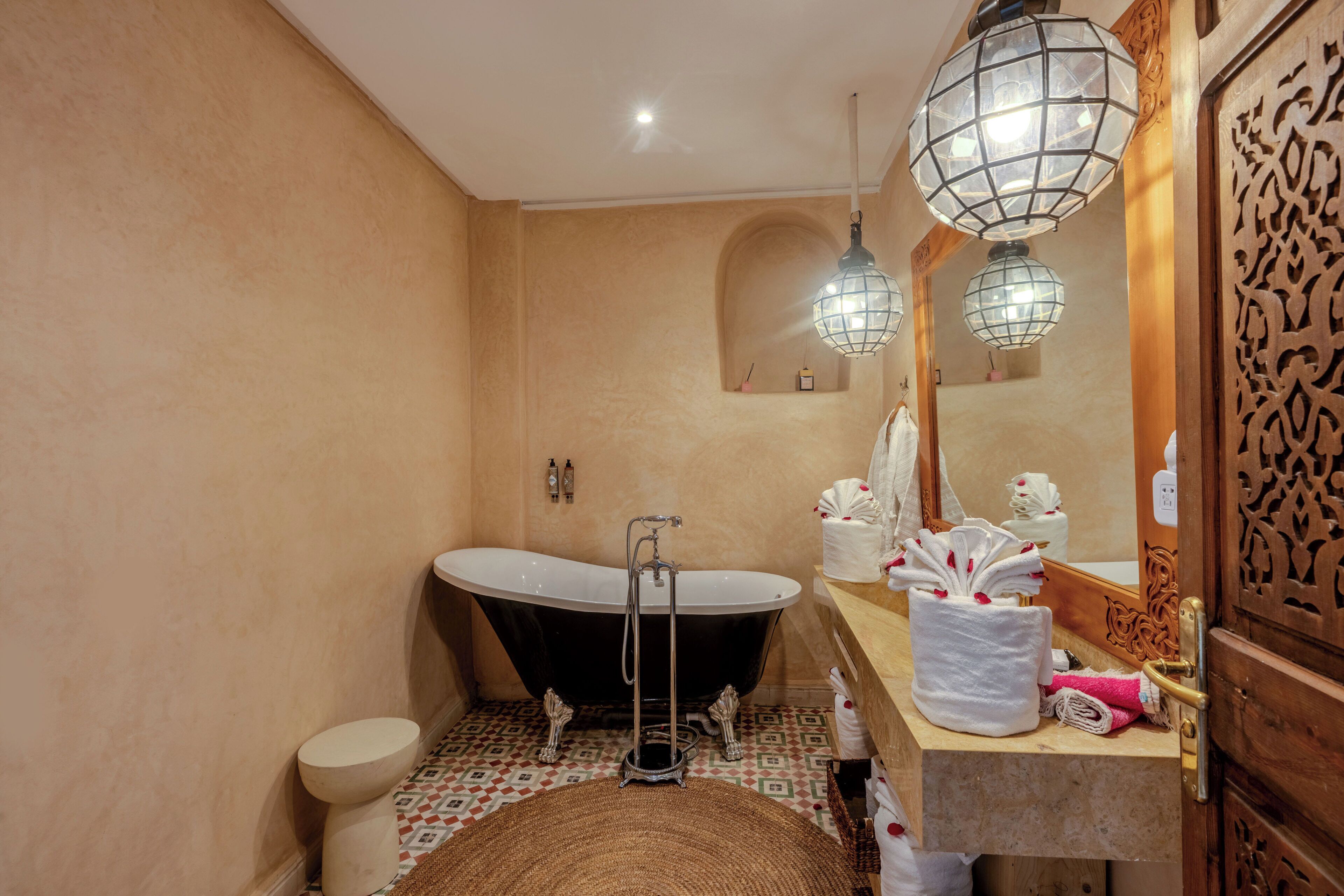 Une salle de bain avec une baignoire sur pieds, des toilettes, un lavabo avec un miroir et des appliques murales décoratives.